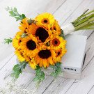 Bouquet of sunflowers and daisies tied with white ribbon on stack of books.