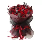 Bouquet of red roses, eucalyptus, and decorative elements wrapped in pink and black fabric.