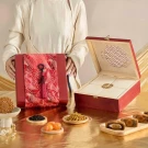 Red gift box with mooncakes and tassels, and an open wooden box with mooncake compartments.