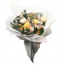 A bouquet of yellow and pink roses with greenery, wrapped in white and gray paper.