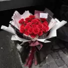 A bouquet of red roses with pearls, wrapped in decorative paper and ribbons, with a "Happy Day" card.