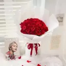 A large bouquet of 66 red roses, wrapped in white paper and tied with a red ribbon.