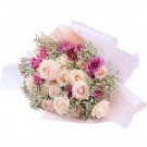 Bouquet of light pink and deep pink roses with white filler flowers, wrapped in pale pink and white paper.