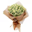 Bouquet of white and yellow chamomile flowers wrapped in burlap and tied with a brown ribbon.