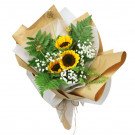 A bouquet of three sunflowers, baby's breath, and ferns, wrapped in brown and white paper.