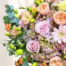 A bouquet of pink roses, peach roses, pink gerbera daisies, and other flowers.