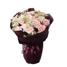 A bouquet of light pink roses and baby's breath wrapped in dark burgundy paper, tied with a ribbon.