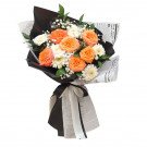 A bouquet of orange roses, white gerbera daisies, and baby's breath in black and newspaper-like paper wrap, tied with a ribbon.