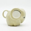 A light beige ceramic mug shaped like a cute elephant, with a handle on the side.