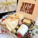 Christmas gift box with knitted scarf, candle, candy cane, and decorative ornaments.
