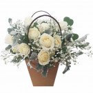 Basket of white roses and baby's breath with green foliage.