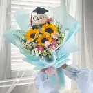 Graduation bouquet with sunflowers, carnations, daisies, and a teddy bear wearing a cap.