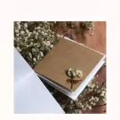 A kraft paper card with dried flowers tied with twine sits on a bed of baby's breath.