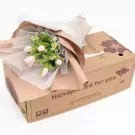 Pink tulips and daisies in a bouquet on a brown cardboard box.