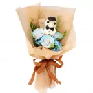 A bouquet with blue roses, hydrangeas, and a cupcake shaped like a teacher, tied with a brown ribbon.
