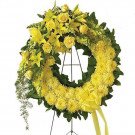 Yellow floral wreath with roses, lilies, and chrysanthemums on a stand.