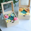 Wooden gift boxes with soap flowers and clear lids.