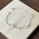 Silver chain bracelet with pink rose quartz beads and small crystal charms.