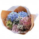 Bouquet of pink, blue, and green hydrangeas with small white daisies, wrapped in brown and white paper.