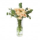 Peach roses and eucalyptus in a clear glass vase.
