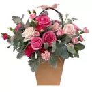A pink and white rose flower basket with carnations and greenery.