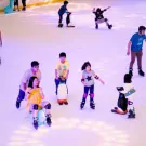 People ice skating at Vincom Landmark 81, with children using penguin helpers.