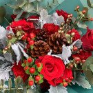 Red roses and carnations with pinecones and berries in a bouquet.