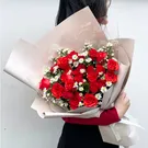 Bouquet of red roses and white daisies in elegant wrapping.