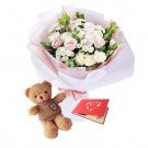 Bouquet of pink and white roses, a teddy bear, and a red card with hearts.