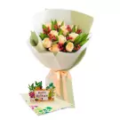 A bouquet of light peach roses with red berries and green leaves next to a 3D pop-up birthday card.