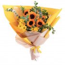 Bright yellow bouquet of sunflowers and yellow daisies with eucalyptus leaves.