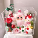 Clear box with plush bunny, bear, flowers, and Christmas decor.