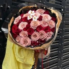 Bouquet of red and pink roses with white flowers and decorative beads.