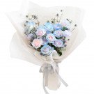 Bouquet of pink and blue roses with thistle, wrapped in white paper and tied with ribbon.