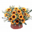 Basket of sunflowers and white flowers with eucalyptus leaves.