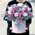Pink box with purple and pink roses and green leaves, tied with a gray ribbon.