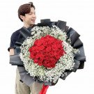 Man holding a large bouquet of 99 red roses and baby's breath.