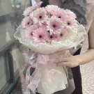 Pink gerbera daisy bouquet with white wrapping and ribbon.