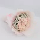Pink roses and baby's breath in a light pink bouquet wrapper.