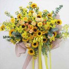 Yellow flower arrangement with sunflowers, roses, orchids, and mums.