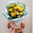 Bouquet of yellow roses with light blue and white wrapping paper.