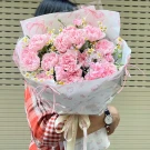 Pink carnation bouquet with Hello Kitty paper wrap held by a person wearing a red and white plaid shirt.