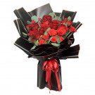 Bouquet of red roses wrapped in black paper with a red ribbon.