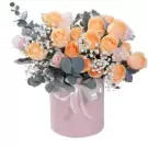 Pink box with peach and pink roses and baby's breath, decorated with a white ribbon.