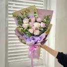 Bouquet of pink and white roses with eucalyptus and lavender wrapping, tied with a pink ribbon.