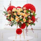 Floral arrangement of peach roses, white lisianthus, and red accents on a wooden stand.