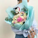 Graduation bouquet with teddy bear in cap, white and pink roses, carnations, and chrysanthemums.