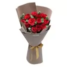 Bouquet of red roses with eucalyptus, wrapped in brown paper and tied with a gold ribbon.