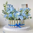 Blue flower arrangement with rolled banknotes around the base, tied with a blue ribbon.
