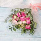 Pink roses, gerbera daisies, baby's breath, and eucalyptus in a bouquet.